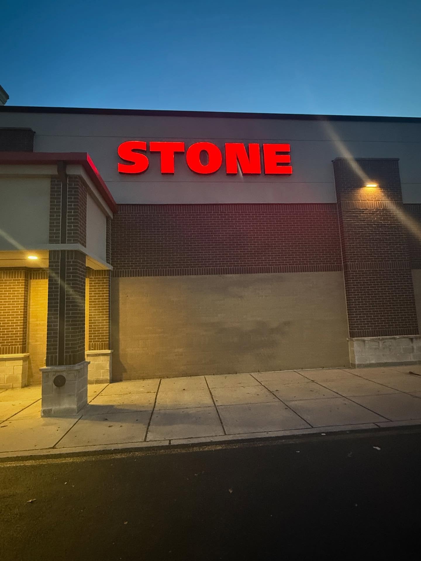 Illuminated STONE channel letters glowing at night